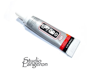 Pode incluir: Um tubo de cola multiusos B-7000. O tubo prateado tem texto a preto e branco, incluindo "B-7000" num retângulo preto. O tubo também tem uma faixa vermelha com texto branco e um bico branco. Contém 9 ml de cola.