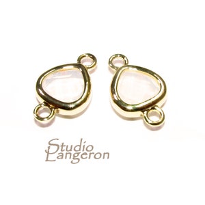 May include: Two gold-tone metal connector charms with a clear glass teardrop shape. Each charm has two jump rings for attaching to jewelry.