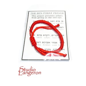 May include: Red string bracelet with Hebrew text on a white card. The card reads "The Ben Porat Prayer. This prayer prevents others from giving us the evil eye."