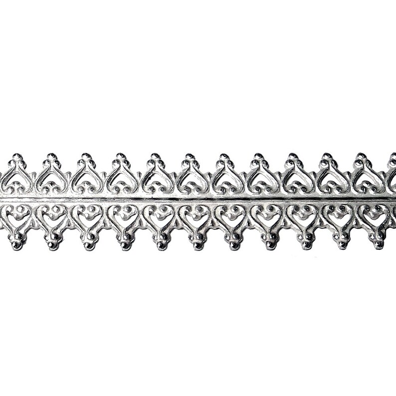 Peut inclure: Garniture en m&eacute;tal argent&eacute; avec un motif d&eacute;coratif compos&eacute; de c&oelig;urs r&eacute;p&eacute;t&eacute;s.