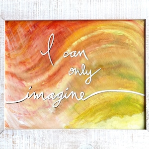 May include: A framed painting with a yellow, orange, and red abstract background. The words "I can only imagine" are written in white cursive on the canvas.
