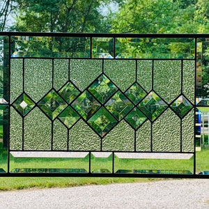 May include: A stained glass window with a geometric design featuring a diamond pattern. The glass is clear with a textured surface and is framed in black.