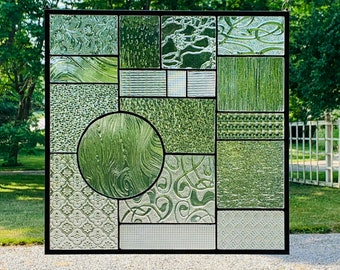 May include: A stained glass window with a geometric design featuring various shades of green glass. The window is divided into 16 squares, each with a different pattern.