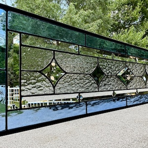 May include: A stained glass window with a geometric design featuring diamond shapes. The glass is clear with a textured surface and the window is framed in black.