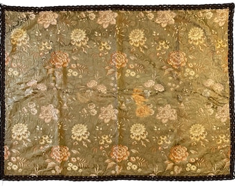 May include: A green fabric with a floral pattern. The fabric has a brown border and is made of a soft, luxurious material.