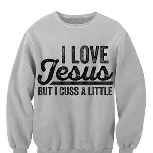 May include: A gray sweatshirt with the text "I love Jesus but I cuss a little" printed on the front.