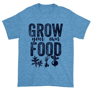 May include: A light blue t-shirt with the text "Grow your own food" in a dark blue distressed font. The text is surrounded by images of various vegetables, including a beet, a garlic bulb, and two leafy greens.