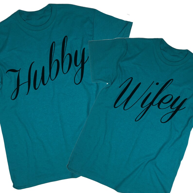 Puede incluir: Dos camisetas de color azul turquesa con las palabras "Hubby" y "Wifey" impresas en letra cursiva negra.