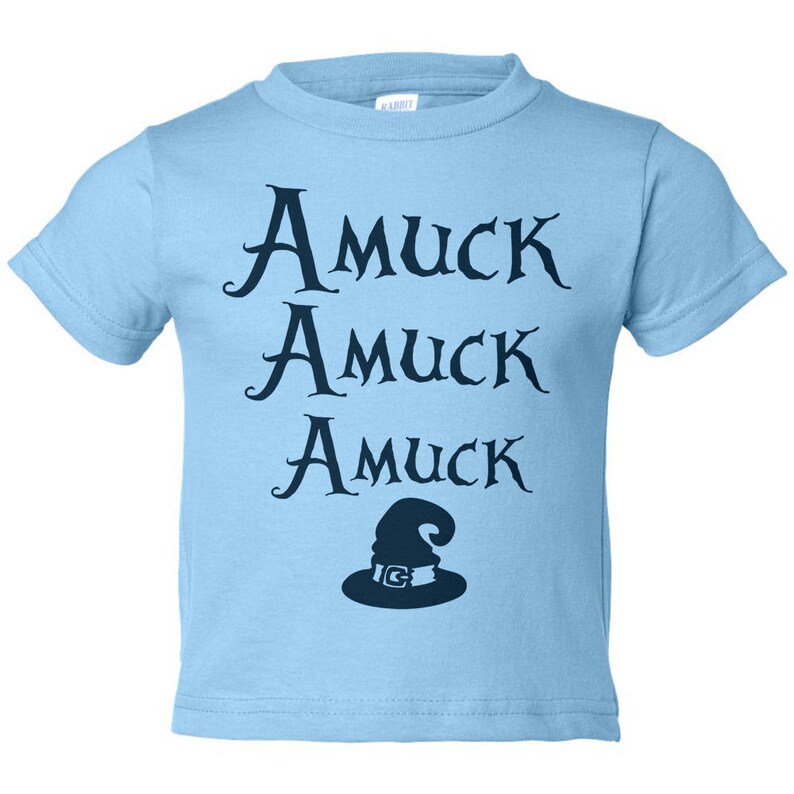 Pu&ograve; includere: Una maglietta azzurra per bambini con le parole "Amuck Amuck Amuck" in corsivo blu scuro. Sotto, un cappello da strega blu scuro con fibbia argentata. La maglietta &egrave; in materiale morbido.