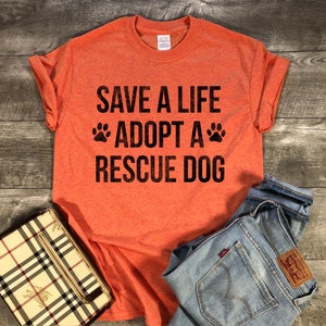 May include: Orange t-shirt with the text "Save a life Adopt a Rescue Dog" in black with paw prints on either side of the word "Adopt".