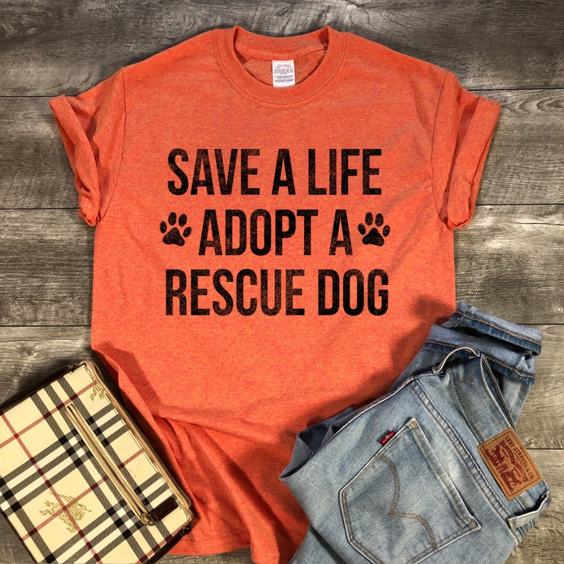May include: Orange t-shirt with the text "Save a life Adopt a Rescue Dog" in black with paw prints on either side of the word "Adopt".
