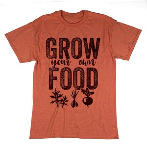 May include: A rust-colored t-shirt with the text "Grow your own food" in black lettering. The shirt features a graphic of three different plants in black.