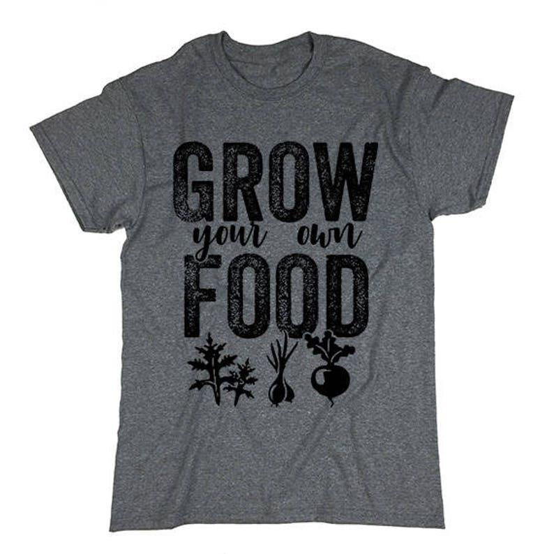 May include: Gray t-shirt with the text "Grow your own food" in black. The text has a distressed look. There are small black illustrations of vegetables below the text.