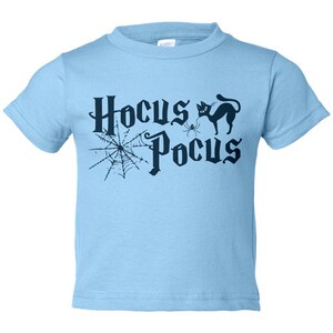 K&ouml;nnte beinhalten: Hellblaues T-Shirt mit einer schwarzen Grafik einer Spinne, einer schwarzen Katze und dem Text "Hocus Pocus".