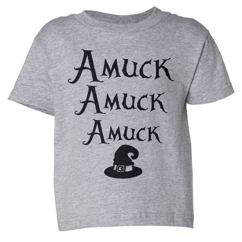 Pu&ograve; includere: Una maglietta grigio melange con le parole "Amuck Amuck Amuck" in corsivo nero e una grafica di cappello da strega nero. La maglietta &egrave; a girocollo e maniche corte.