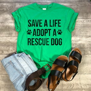 May include: Green t-shirt with the text "Save a Life Adopt a Rescue Dog" in black with paw prints on either side of the word "Adopt".