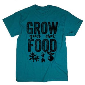 May include: Teal blue t-shirt with the text "Grow your own food" in black. The text has a distressed look. There are three black silhouettes of plants below the text.