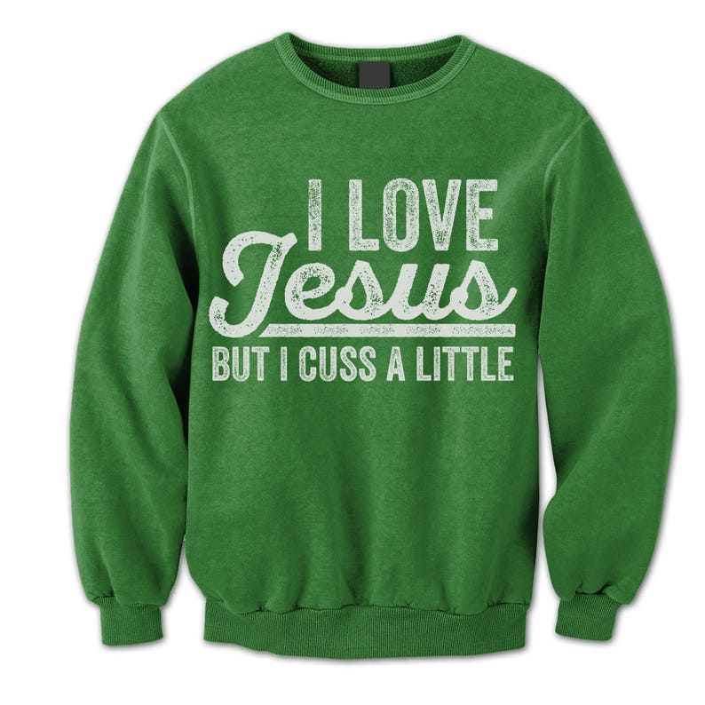 May include: Green sweatshirt with a white distressed graphic that reads "I Love Jesus But I Cuss A Little."