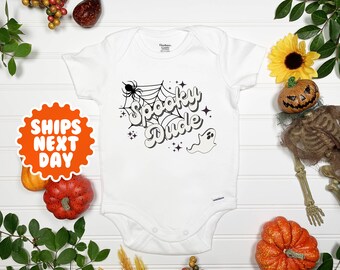 May include: White baby onesie with a black and white graphic design that says "Spooky Dude" with a spider web, spider, and ghost.