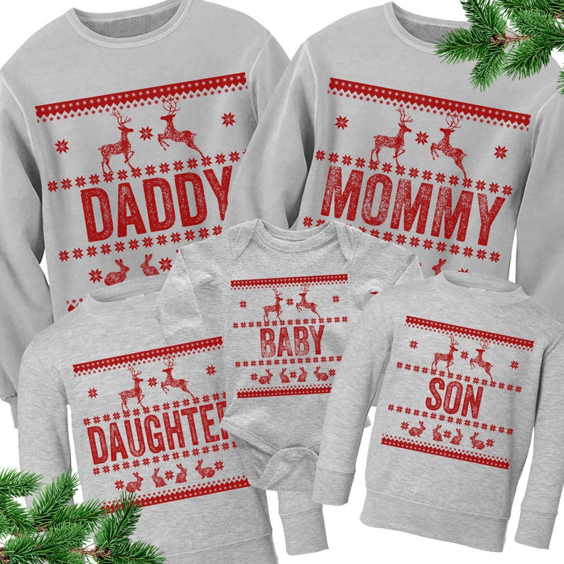 Op de afbeelding: Een set van vijf grijze kersttruien met rode rendier- en sneeuwvlokmotieven. De truien hebben de woorden "Daddy", "Mommy", "Baby", "Daughter" en "Son" erop gedrukt.