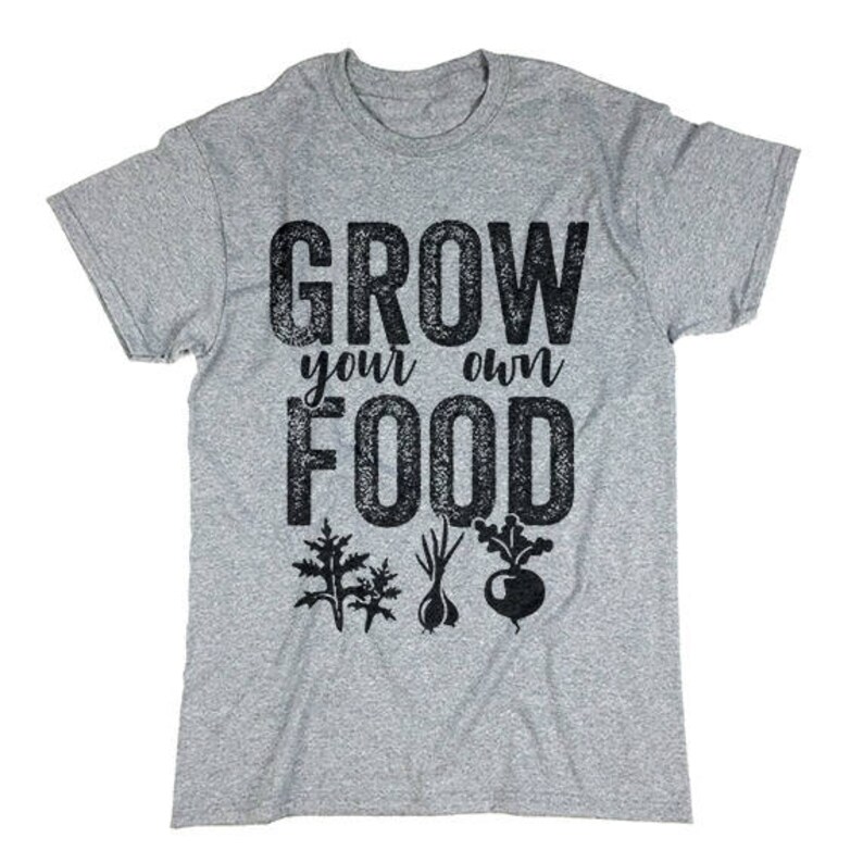 May include: Gray t-shirt with the text "Grow your own food" in black with a distressed look. The text is surrounded by small black graphic images of plants.