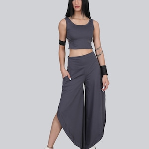Könnte beinhalten: Ein zweiteiliges Outfit in Dunkelgrau. Das Oberteil ist ein bauchfreies Tanktop, die Hose ist eine weite Hose mit Taschen. Das Model trägt weiße Turnschuhe. Das Outfit ist aus einem weichen, fließenden Stoff gefertigt.