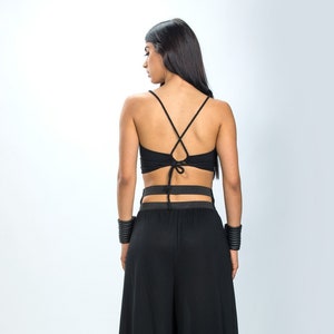 May include: A black crop top with a criss-cross back and a matching pair of wide-leg pants. The pants have a wide waistband with a cut-out detail.