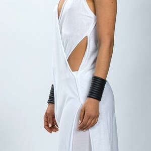 May include: White sleeveless tunic with a deep V-neckline and side slits. The tunic is made of a soft, flowing fabric and has a relaxed fit.
