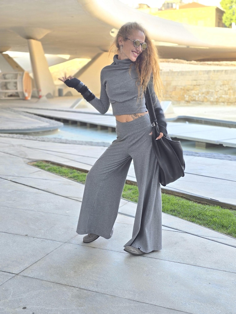 May include: A woman wearing a gray ribbed turtleneck top and matching wide-leg pants. She is wearing sunglasses and has a black bag slung over her shoulder.