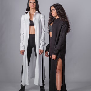 May include: Two people wearing long cardigans, one white and one black, with black leggings and black boots.