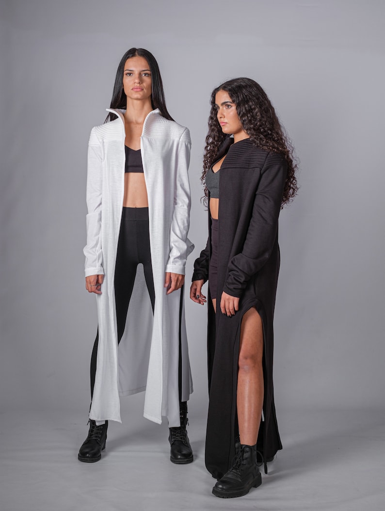 May include: Two people wearing long cardigans, one white and one black, with black leggings and black boots.