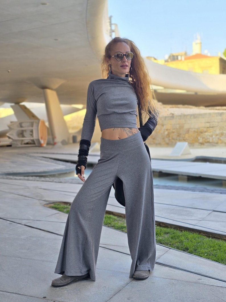 May include: A gray ribbed knit top and wide-leg pants set. The top has a high neck and long sleeves. The pants have a wide leg and a high waist.