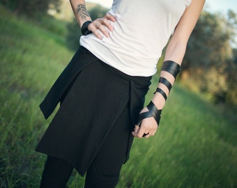 May include: A black wrap skirt with a white tank top. The skirt is tied at the waist and has a long, flowing design.