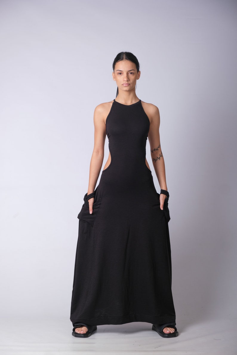 May include: A black maxi dress with a halter neckline and cutouts on the sides. The dress is made of a soft, stretchy fabric and has a flowing silhouette.