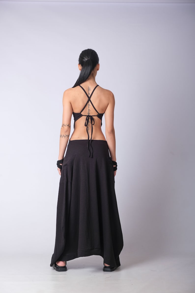 May include: A black, sleeveless top with a criss-cross back tie and a matching black maxi skirt. The skirt has a loose, flowing fit and a unique asymmetrical hemline.