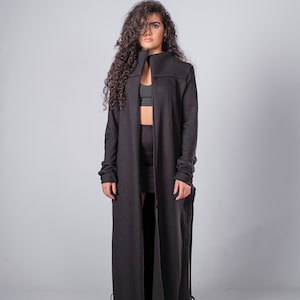 May include: A long black cardigan with a high collar and long sleeves. The cardigan is open in the front and has a long, flowing design.