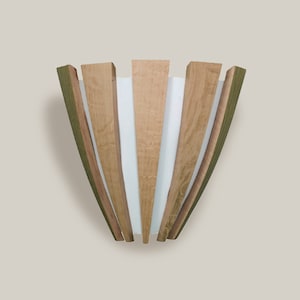 Peut inclure: Applique murale en bois avec un design en forme d'éventail. L'applique présente des lattes de bois alternées en marron clair et foncé, avec des panneaux blancs entre elles. Les bords extérieurs sont d'un brun-vert plus foncé.