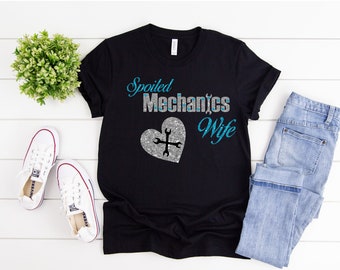 May include: Black t-shirt with silver glitter text that reads "Spoiled Mechanics Wife" with a silver glitter heart containing a wrench and screwdriver in blue.