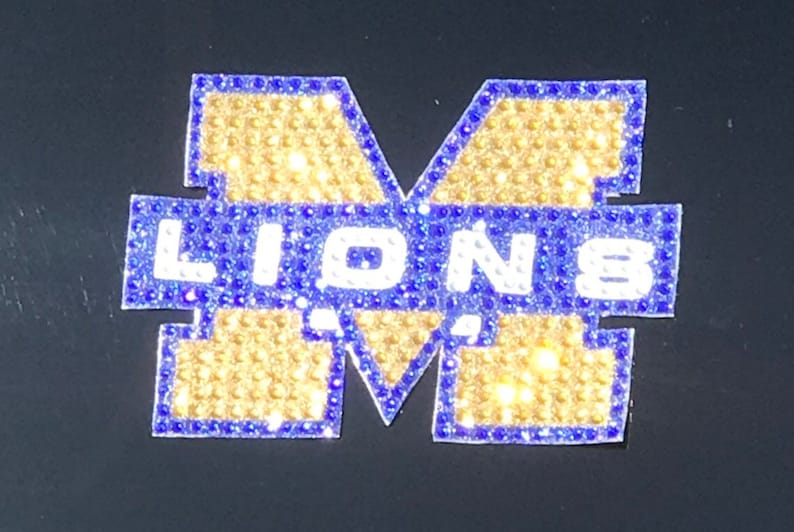 May include: A blue and gold iron-on patch with the letter "M" and the word "LIONS" in white.