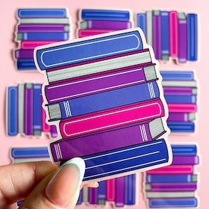 May include: A stack of colorful book stickers with a variety of purple, blue, pink, and white stripes. The stickers are arranged in a stack with the top sticker being a dark blue with white stripes.
