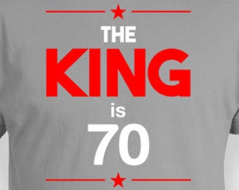 Może przedstawiać: Szara koszulka z czerwonym napisem "The King is 70".