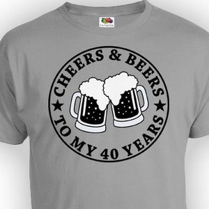Puede incluir: Una camiseta gris con un gr&aacute;fico circular negro que dice "Cheers & Beers to My 40 Years" con dos jarras de cerveza que brindan.