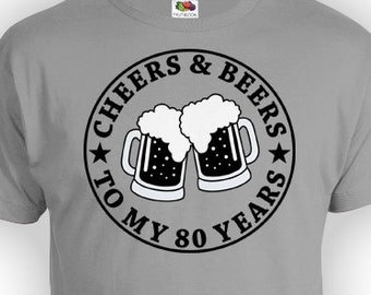 Puede incluir: Camiseta gris con un gráfico circular negro que dice "Cheers & Beers to My 80 Years" con una imagen de dos jarras de cerveza brindando.