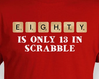 以下が含まれることがあります： スクラブルのタイルで「EIGHTY」という単語が綴られた、「EIGHTY IS ONLY 13 IN SCRABBLE」と書かれた白いグラフィックが施された赤いTシャツです。