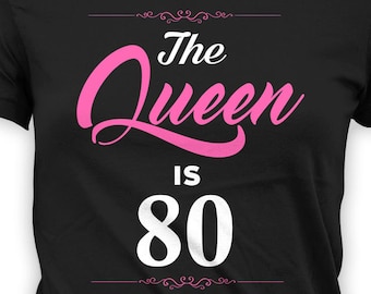 May include: Black t-shirt with pink text that reads "The Queen is 80".