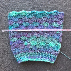 May include: A crocheted headband in shades of green, purple, and blue, measuring 7 inches in diameter.