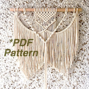 May include: A beige macrame wall hanging with a geometric pattern and fringe. The hanging is attached to a wooden dowel. The text "*PDF Pattern" is visible in the lower left corner of the image.