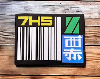Könnte beinhalten: Schwarz-weißer Barcode mit dem Text "7HS" in gelben Buchstaben. Rechts neben dem Barcode befindet sich ein grünes und blaues Quadrat mit japanischen Schriftzeichen.
