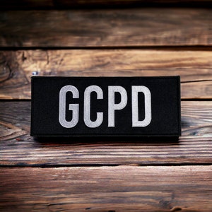 May include: Black patch with white embroidered text that reads "GCPD".