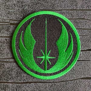 May include: Green embroidered patch with the Jedi Order symbol. The symbol features a lightsaber, a star, and two wings.
